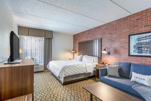 a hotel room with a bed and a couch at Burrstone Inn, Ascend Hotel Collection in Utica