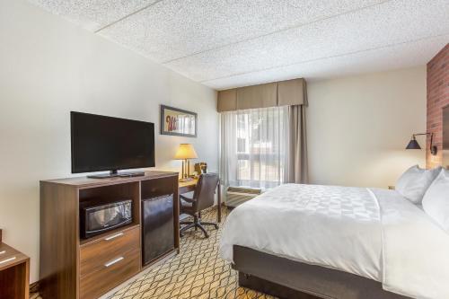 a hotel room with a bed and a flat screen tv at Burrstone Inn, an Ascend Collection Hotel in Utica