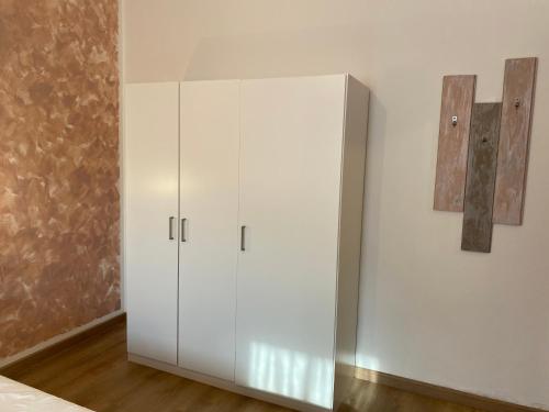 a white cabinet in a bedroom with two pictures on the wall at Casa Belvedere in Pieve di Cadore