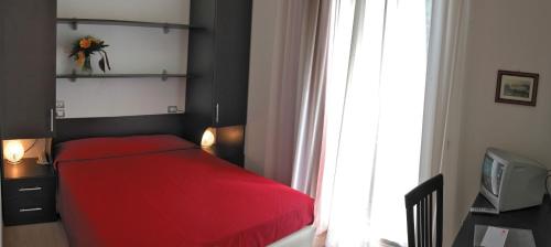 a red bed in a bedroom with a window at Hotel Morolli in Rimini