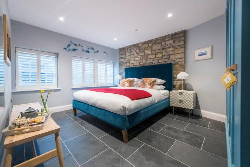 a bedroom with a blue bed and a brick wall at Iris 5 Star Gold Award Luxury Cottage in St Ives