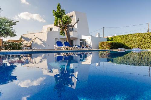 una piscina con sillas azules y una casa en STARBAL Love, en Es Castell