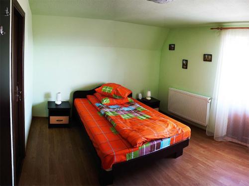 a bed with an orange comforter in a bedroom at Cabana Andreea Telescaun in Ranca