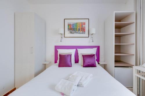 ムアン・サルトゥーにあるHôtel CasaBellaの紫色をアクセントにした白いベッドが備わるベッドルーム1室