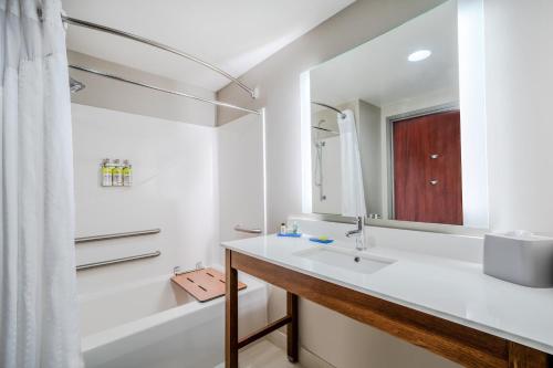 a bathroom with a sink and a tub and a mirror at Holiday Inn Express Hotel & Suites Tappahannock by IHG in Tappahannock