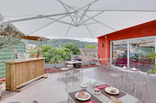 a patio with tables and chairs and an umbrella at Hôtel CASABELLA Cannes Mouans Sartoux in Mouans-Sartoux