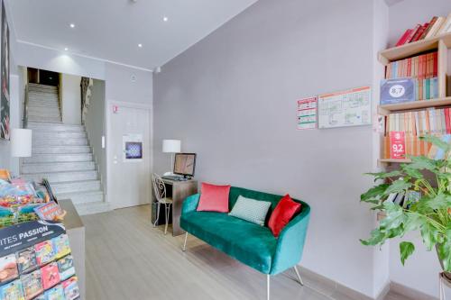 a living room with a green couch and a staircase at Hôtel CasaBella in Mouans-Sartoux