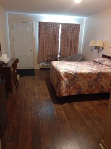a hotel room with a bed and a desk and a window at Motel Vaudreuil in Vaudreuil-Dorion