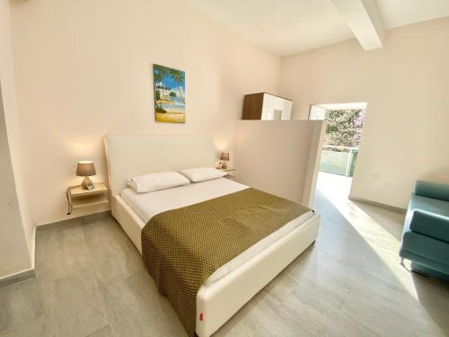 a white bedroom with a bed and a blue chair at Guesthouse Riviera "XH&M" Dhermi in Dhërmi