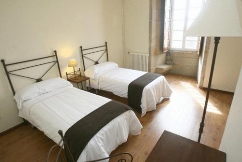a bedroom with two beds and a table and a lamp at Hospedería San Martín Pinario in Santiago de Compostela