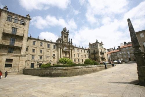 a large building with a clock tower in a city at Hospedería San Martín Pinario in Santiago de Compostela