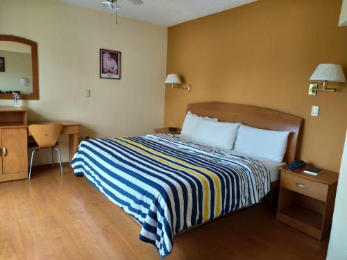 a hotel room with a bed with a striped blanket at Hotel Florencia Regency in Morelia