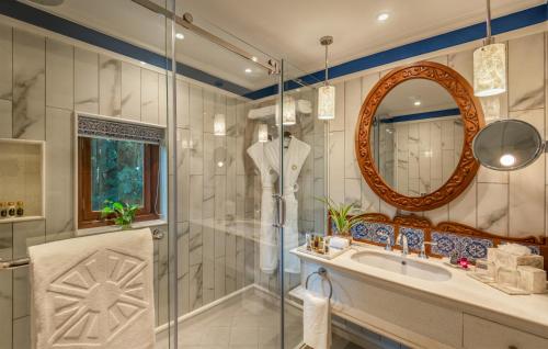 a bathroom with a shower and a sink and a mirror at Taj Holiday Village Resort & Spa, Goa in Candolim