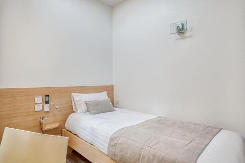 a small bedroom with a bed and a chair at Hôtel des Voyageurs Centre Bastide in Bordeaux