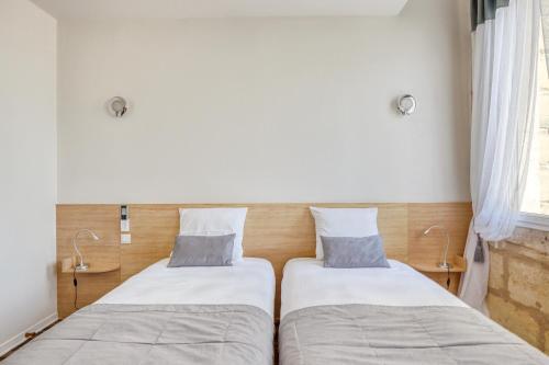 two beds sitting next to each other in a room at Hôtel des Voyageurs Centre Bastide in Bordeaux