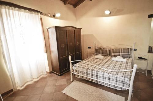 a bedroom with a bed with a plaid blanket and a window at Casa De Ajala - B&B de Charme in Antica Dimora totalmente ristrutturata e dotata di tutti i confort Bagni privati Spazio living Patio esterno Ambienti climatizzati Degustazioni prodotti locali in Làconi