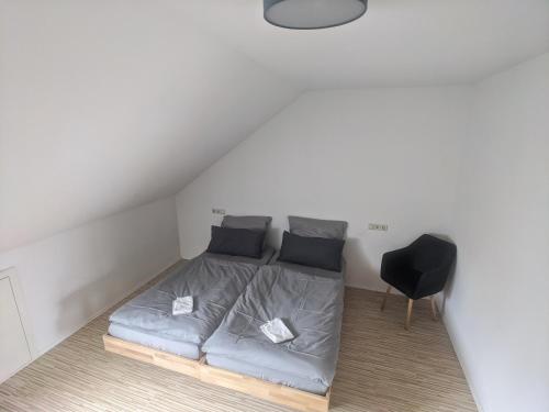 a bed in a small room with a black chair at Über den Dächern von Kirchheim, Modernes Apartment in Kirchheim unter Teck