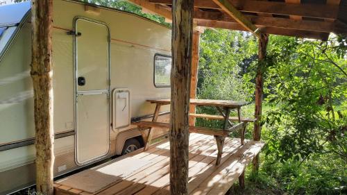 an outside porch of an rv with a bench at Caravan Yard in Valdemārpils