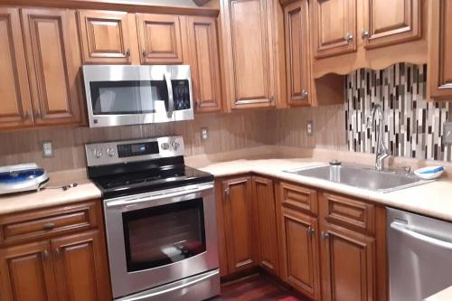 a kitchen with wooden cabinets and a stove and a microwave at Lovely oasis with private swimming pool 4,6,8 f deep in Gulf Breeze