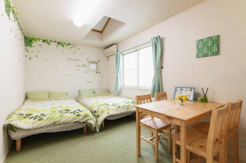 a room with two beds and a table and a desk at City Garden - Vacation STAY 87278 in Fukuoka