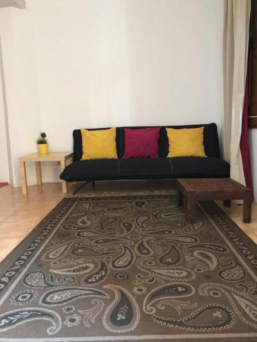 a living room with a black couch with colorful pillows at Casas Botelho Elias in Pinhão