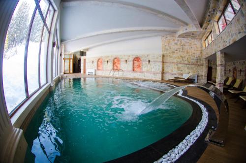 a pool with a waterfall in a building with windows at Complex Kamelia in Pamporovo