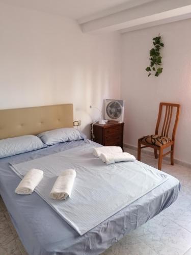 a bed with two pillows and a chair in a bedroom at PISO EN MALVARROSA in Valencia