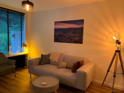 a living room with a couch and a lamp at Rode Eekhoorn: genieten met de dieren in het bos! in Otterlo