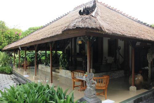 a pavilion with chairs and a table and a thatch roof at Tandjung Sari Hotel in Sanur