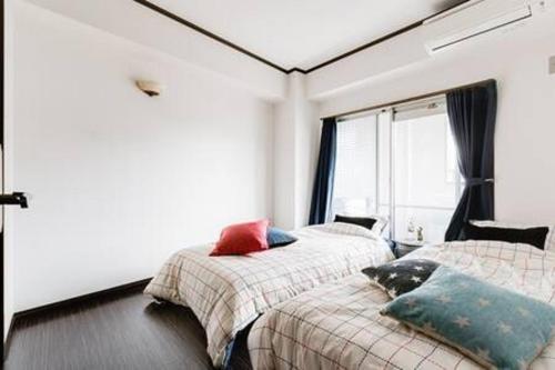 a bedroom with two beds and a window at Il Sole Kujo - Vacation STAY 8471 in Osaka