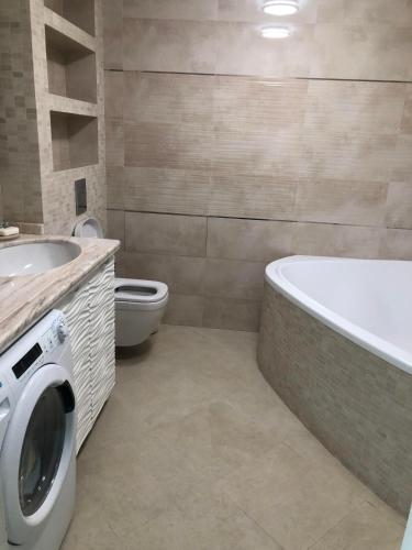 a bathroom with a tub and a toilet and a washing machine at Comfy Retreat on Kotsubinsky street in Vinnytsya