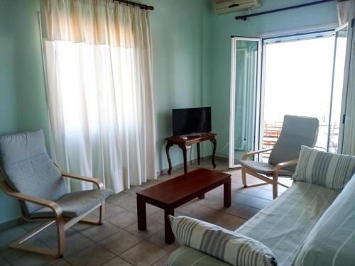ein Wohnzimmer mit einem Sofa, Stühlen und einem TV in der Unterkunft Marinis House in Koroni