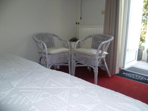 a bedroom with two chairs and a bed at Hotel Pension Oranje in Valkenburg