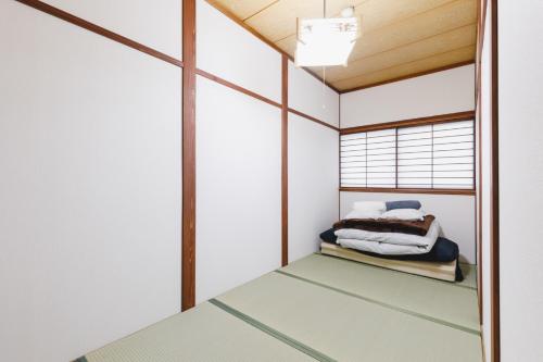 Habitación pequeña con cama y ventana en Couch Potato Hostel - Vacation STAY 88233, en Matsumoto