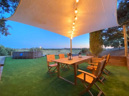 a wooden table and chairs under an umbrella at Mas de l'Aranyó - Eco Wellness Spa in Hostafranco