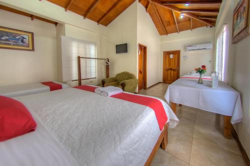 a bedroom with two beds and a chair and a table at Hotel San Vicente Galapagos in Puerto Villamil