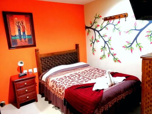 a bedroom with a bed and a tree mural on the wall at Hotel Amayal in San Cristóbal de Las Casas
