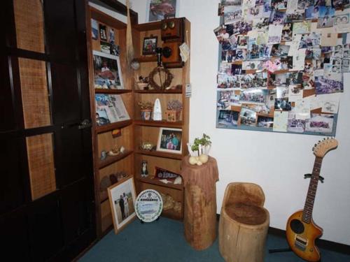 a room with a guitar and a shelf with pictures at Allumeur in Minami Uonuma