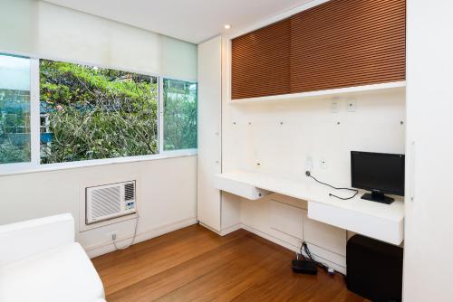 een kamer met een bureau, een tv en 2 ramen bij Beautiful Leblon in Rio de Janeiro