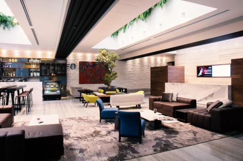 a lobby with couches and chairs and a television at Krystal Grand Suites Insurgentes in Mexico City