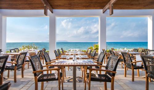 an outdoor dining area with tables and chairs and the ocean at The Island Hotel - Adults Only - in Gouves