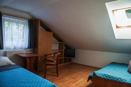 a room with two beds and a desk and a window at Dom Gościnny "Satori" in Pogorzelica