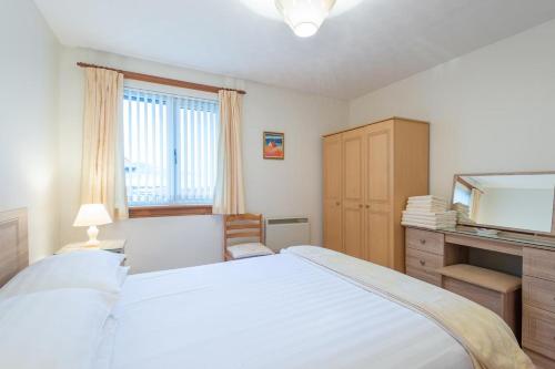 1 dormitorio con 1 cama blanca grande y espejo en Clisham, en Beauly