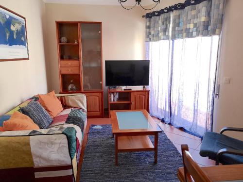 a living room with a couch and a flat screen tv at Home By The Sea in Sesimbra
