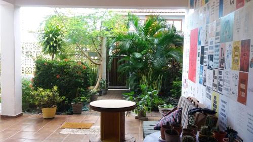 Slow Hostel - Hospedagem Criativa في جواو بيسوا: غرفة مع طاولة في وسط غرفة بها نباتات