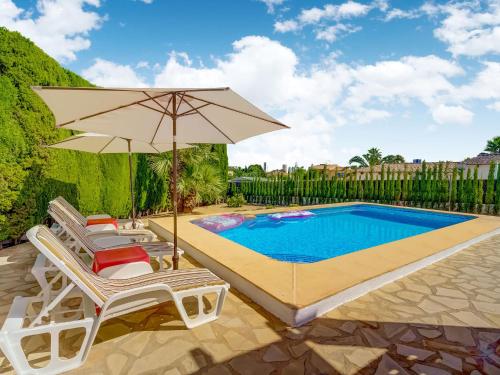 una piscina con due sedie e un ombrellone di Belvilla by OYO La Casita a Calpe