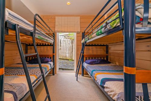 a bunk bed room with three bunk beds in a cabin at Opoutere Oasis - Opoutere Holiday Home in Opoutere