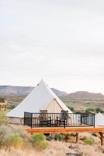 a large white tent with a deck in the desert at Zion Wildflower Resort in Virgin