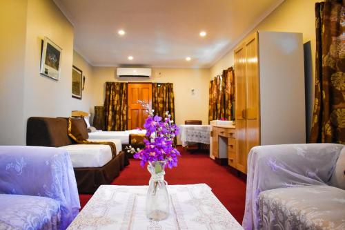 a living room with a vase of purple flowers on a table at Grand Eastern Hotel in Labasa