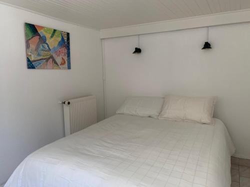 a white bed in a white bedroom with a picture on the wall at INTERLUDE omaha beach 50 m de la plage in Saint-Laurent-sur-Mer